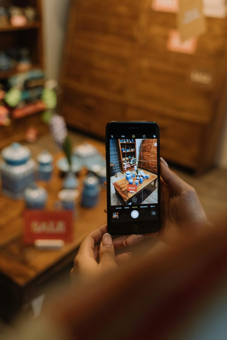 Hands holding a smartphone to photograph sale items in a boutique, showcasing shopping and mobile photography.